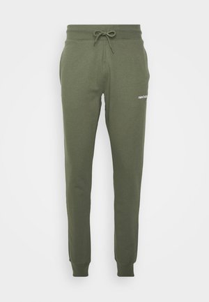 Olivgrüne Jogginghose mit elastischem Bund, Kordelzug, Seitentaschen, Bündchen an den Knöcheln und kleinem weißen "new balance"-Logo am rechten Oberschenkel.