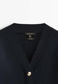 Cardigan bleu marine à col en V en tissu tricoté doux avec un bouton décoratif doré à l'avant. Étiquette indiquant "Massimo Dutti".