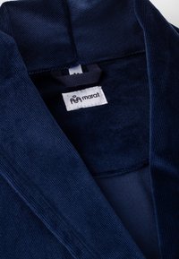 Laivastonsininen samettikangaspinta, jossa on tekstuuri, ja tunniste, jossa lukee "marat." Kaulus on hieman auki, paljastaen yhtenäisen sisäpuolen.