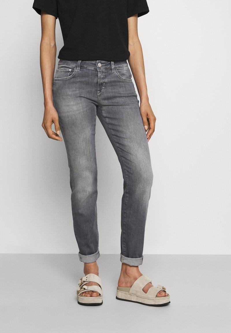 Personne portant un jean gris retroussé, un haut noir à manches courtes et des sandales à plateforme beige avec double brides et boucles.
