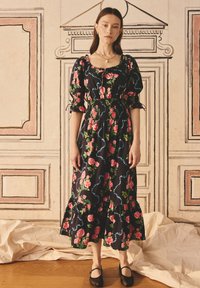 Rochie florală neagră cu mâneci bufante și talie elastică. Prezintă trandafiri roz și accente albastre. Lungime midi cu o margine volan.