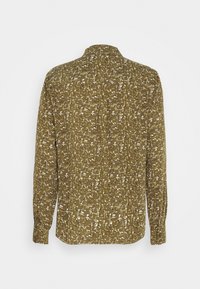 Chemise à manches longues avec un motif camouflage abstrait vert et beige, vue de dos sur un fond clair uni.
