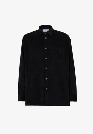 Camicia nera in corduroy con maniche lunghe, chiusura frontale con bottoni, colletto a punta e taschino sul petto sinistro con dettagli del logo in rilievo.