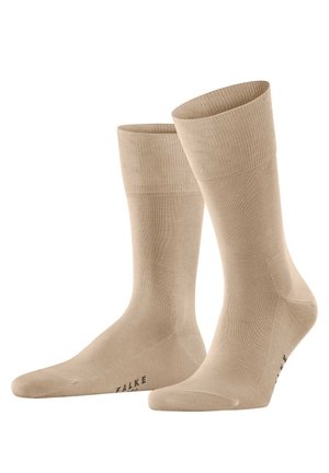 Beige cotton socks with a ribbed cuff and smooth texture, featuring a reinforced toe and slight sheen. Brand name "FALKE" printed on the sole.
