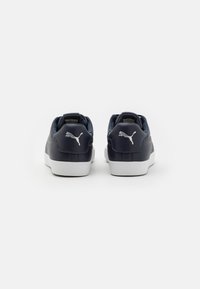 Mornarsko modri usnjeni športni copati z belimi gumijastimi podplati. Imajo oblazinjeni ovratnik in beli Puma logotip na peti. Gladka tekstura in zaobljen oblik.