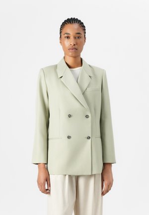 Dobbeltspent blazer i lys grønn stoff, med notched krage, to knapper og brystlomme. Strukturert design med glatt tekstur.