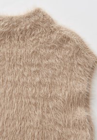 Gilet lavorato a maglia beige con una texture morbida e pelosa e un collo alto. Presenta un design loose-fitting con un leggero taglio asimmetrico.