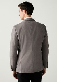 Grau strukturierter Blazer mit einer taillierten Form, einreihigem Design und Dreiknopfverschluss an den Ärmeln. Glatte Stoffqualität mit maßgeschneiderten Rückennähten.