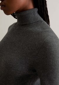 Gray ribbed turtleneck sweater with a fitted design and high collar. Textured fabric and slightly structured shoulder seam.