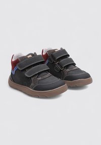Zapatos para niños en negro y marrón, fabricados con materiales sintéticos, con dos correas de velcro, cuello acolchado y suela de goma texturizada.
