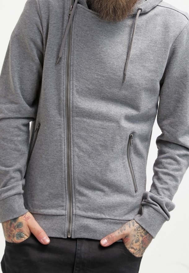 Sudadera con capucha gris con cierre de cremallera diagonal, confeccionada con tela suave, que incluye dos bolsillos laterales con cremalleras y puños acanalados.