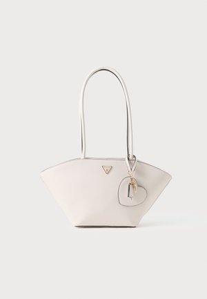 Beige tote bag met twee lange handvaten, driehoekige vorm, gestructureerd oppervlak, gouden logo en hartvormige sleutelhanger detail.