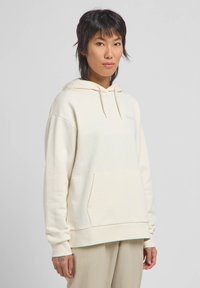Felpa con cappuccio in morbido tessuto crema, dotata di una tasca frontale, polsini elasticizzati e un logo discreto sul petto. Texture liscia, vestibilità comoda.