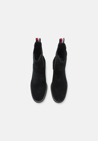 Bottines en daim noir avec des panneaux latéraux élastiques, un bout arrondi et une languette avec des rayures rouge, blanc et bleu au talon.