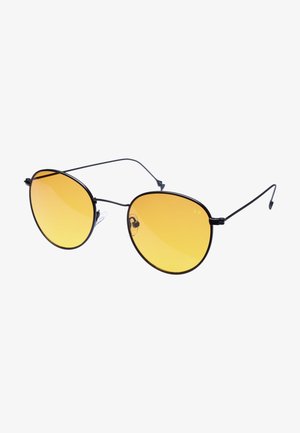 Gafas de sol de gran tamaño con lentes redondos de tinte dorado. Montura delgada de metal negro y puntas de las patas, con almohadillas nasales para mayor comodidad.