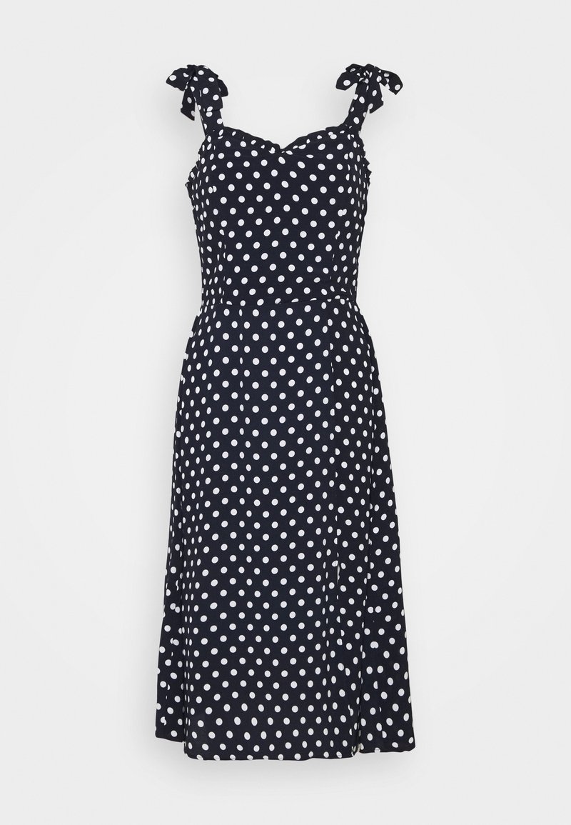 Marineblauwe jurk met witte polkadots, verstelbare strikbandjes, V-hals, aangesloten lijfje en uitlopende rok. Soepele textuur, kniehoogte.