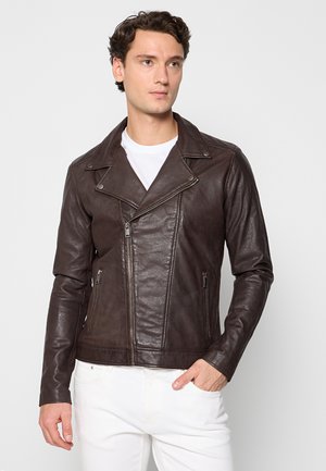 Brązowa skórzana kurtka motocyklowa o wyraźnej konstrukcji, z klapami w kształcie notcha, asymetrycznym zamkiem i dwoma bocznymi kieszeniami. Lekka tekstura, dopasowany krój.