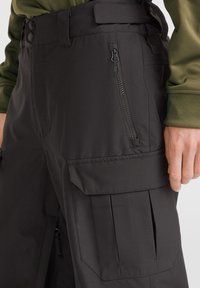 Sorte tekniske bukser med en glat overflade, der har en sidelomme med lynlås, flad front og detaljeret cargo-lomme design.