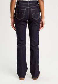 Dark blue flared jeans made from denim. Features include two back pockets with curved stitching and a waistband with belt loops.