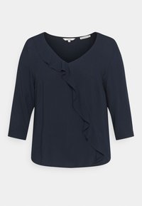 Top blu navy con scollo a V e maniche a tre quarti, caratterizzato da un dettaglio di rouches verticali lungo il davanti e una texture del tessuto liscia.