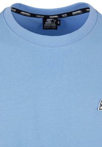 Light blue cotton t-shirt with a crew neck, featuring a small logo embroidered on the left side. Soft texture, simple design.
