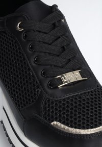 Schwarzer Sneaker mit einem Obermaterial aus Mesh und Leder, runden Schnürsenkeln, silberfarbener Hardware und weißer Sohle mit strukturierten Akzenten.