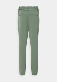 Pantalons verts fuselés avec une texture lisse, taille élastique et deux poches arrière. Design épuré sans motifs ni embellissements visibles.