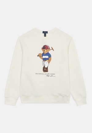 Bílá mikina s motivem medvěda v modro-bílém pruhovaném polu, který drží kladivo, s podpisem Ralph Lauren pod grafikou.