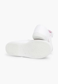 Zapatos blancos con una suela de goma texturizada que presenta patrones florales. La parte superior está hecha de una tela suave con un acabado liso.