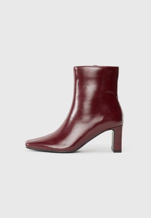 Bordeaux læder ankelstøvle med spids tå, skinnende overflade og firkantet hæl. Har en glat overflade og minimalistisk design.