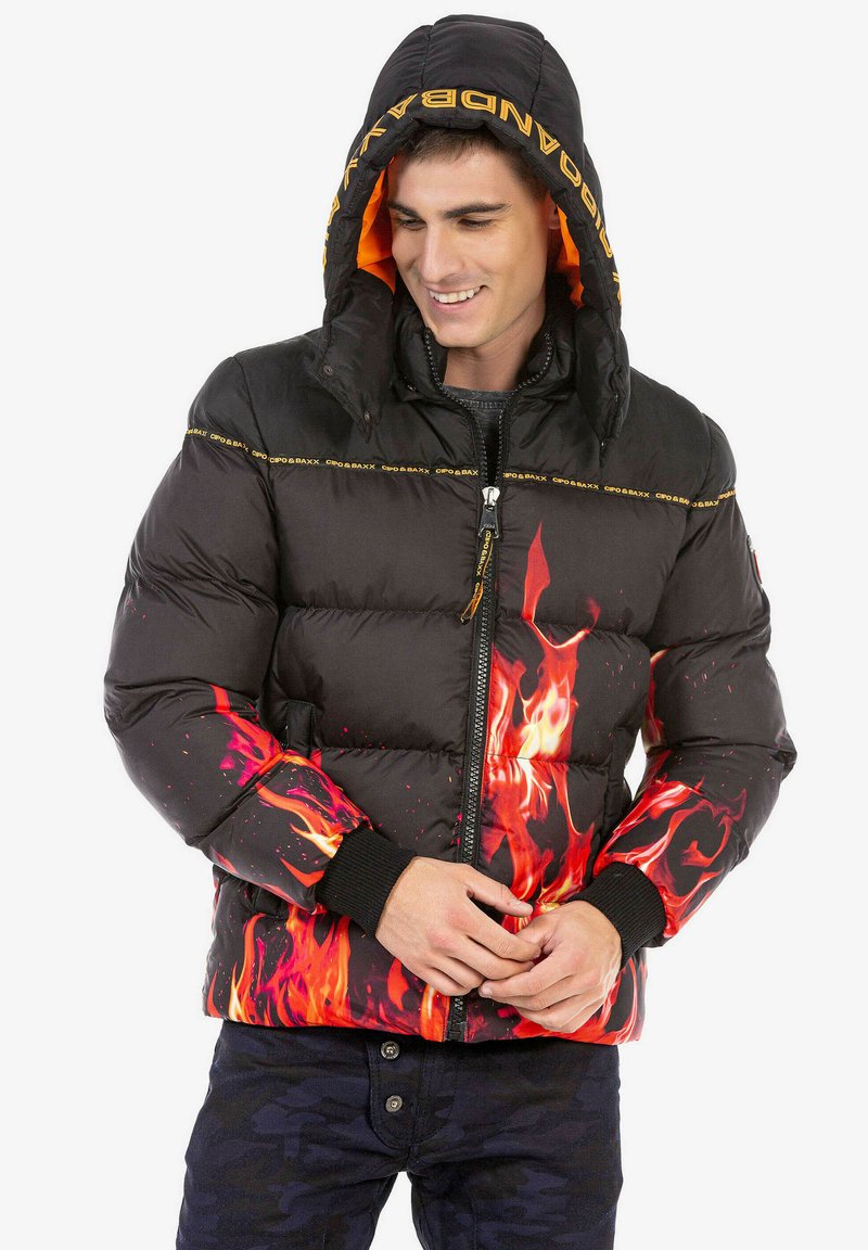 Schwarze Pufferjacke mit roten und orangefarbenen Flammenmotiven, gepolstertem Design, Reißverschluss und abnehmbarem Kapuzenschild mit orangefarbenem Innenfutter.