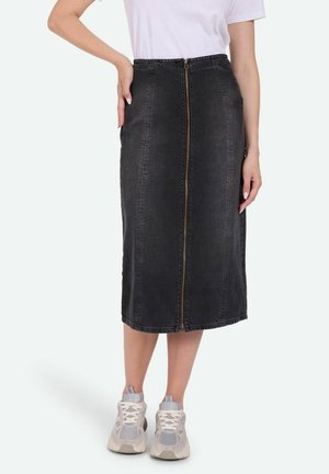 Zwarte denim midi-rok met een ritssluiting aan de voorkant, subtiele stikseldetails en zijzakken, gecombineerd met lichtgrijze sneakers.
