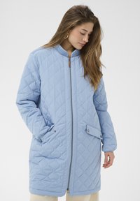 Svetlo modra prešita jakna z vzorcem diamantov, z zadrgo spredaj, rebrastim ovratnikom, stranskimi žepi in poudarki z gumbi na stisnjenje.