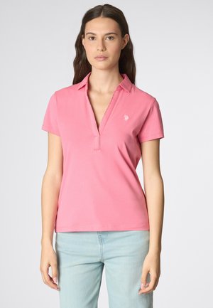 Polo shirt rosa con colletto, maniche corte e design a pullover. Presenta un piccolo logo ricamato sul lato sinistro del petto.