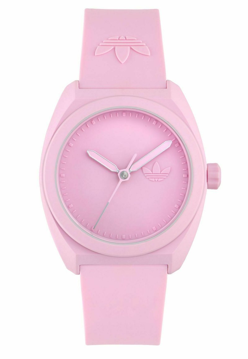 Montre en silicone rose avec un cadran rond, aiguilles des heures et des minutes de couleur rose clair contrastante, et un logo de la marque gravé sur le cadran.