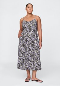 Maxikleid mit Blumenmuster und dünnen Trägern, mit tailliertem Oberteil und ausgestelltem Rock, hauptsächlich in Lila-, Weiß- und Grüntönen.