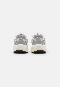 Sport shoes featuring a white mesh upper, gray suede accents, and a thick cream midsole. Rubber outsole with textured grip detail.