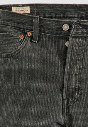 Black denim jeans with a textured finish, featuring a reinforced waistband, copper button, and a label reading "Levi's Premium."