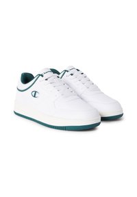 Weiße Low-Top-Sneaker mit grünen Akzenten und Sohlen, mit Schnürdesign und gestickten Logos an der Seite und Zunge, auf weißem Hintergrund.