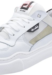 White sneaker with a textured leather upper, mesh panels, and suede accents. Features a padded tongue and laces, with a logo on the side.
