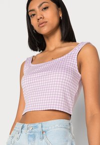 Top cropped em padrão xadrez lilás claro, feito de tecido suave. Apresenta alças largas e um decote quadrado, combinado com calções de cintura alta.