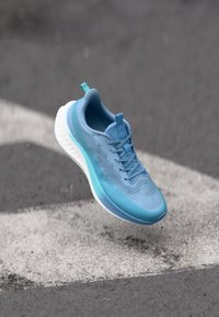 Sapatilha de corrida leve em tons de azul com parte superior em malha e detalhes texturizados, apresentando uma entressola branca e atacadores planos.