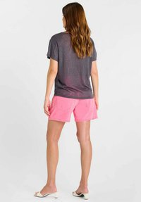 Grijs, kortärmelig T-shirt gemaakt van een zachte stof, gecombineerd met felroze shorts. De shorts hebben zakken en een losse pasvorm. Minimalistisch design.