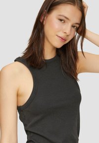Schwarzes, geripptes Tanktop mit rundem Ausschnitt und weiten Armausschnitten, aus einem weichen, texturreichen Stoff und mit figurbetonter Silhouette.