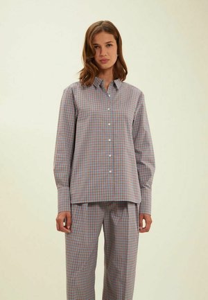Chemise à boutons en motif carré gris clair avec des accents rouges et bleus, présentant des manches longues, un col et une coupe décontractée.
