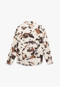 Langarmshirt in crème met een abstracte spetterprint in bruin en zwart. Heeft een kraag en knoopmanchetten. Zachte stofstructuur.