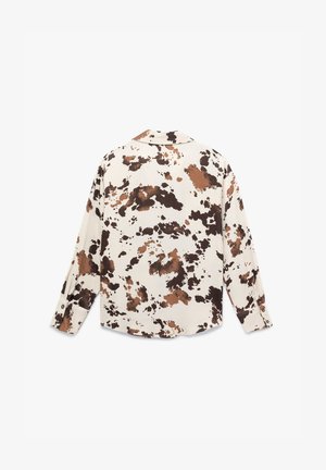 Chemise à manches longues en crème avec un imprimé éclaboussure abstrait marron et noir. Elle a un col et des poignets à boutons. Texture de tissu douce.