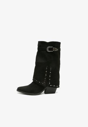 Bottes de cheville en suede noir avec un bout pointu, ornées de clous en argent décoratifs sur le côté et d'une boucle au-dessus de la cheville.