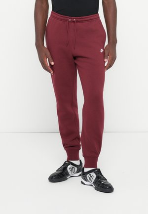 Bordo sporta bikses ar elastīgu jostasvīru un auklu; neliels balts Nike logo kreisajā augšstilbā; apvienotas ar melniem kedām ar sudraba akcentiem.