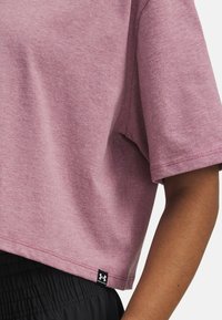 Camiseta corta de manga corta en color rosa, hecha de una tela suave, con una etiqueta de logo negra en el dobladillo y un corte relajado y holgado.
